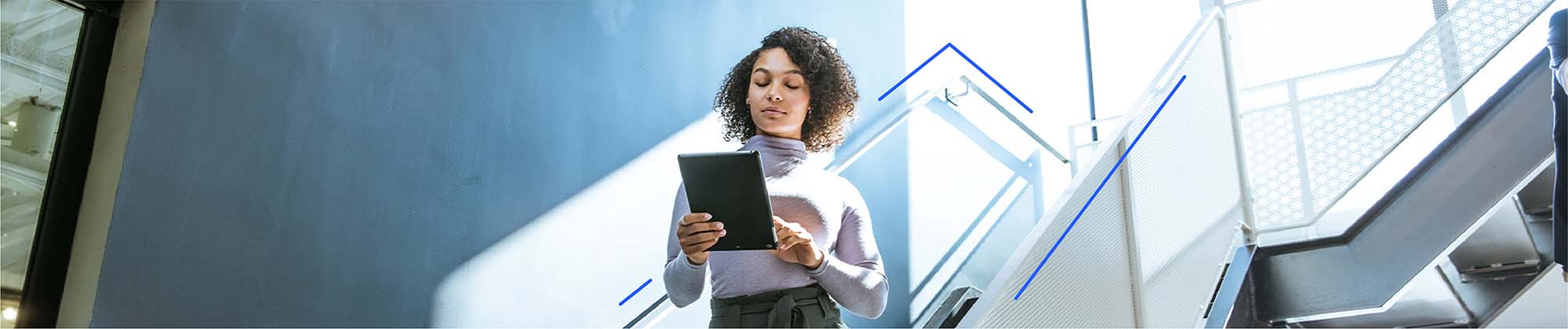 What-Is-a-Good-Download-and-Upload-Speed-skinny-banner woman walking down a brightly lit stairway in an office building using an ipad